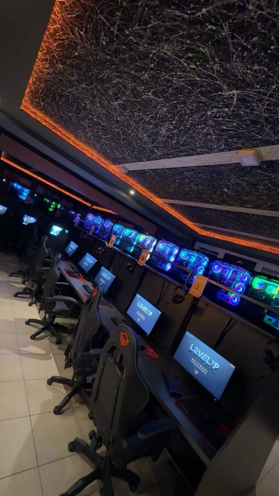 Salla e Level Up me tavan me drita portokalli dhe radhë kompjuterësh